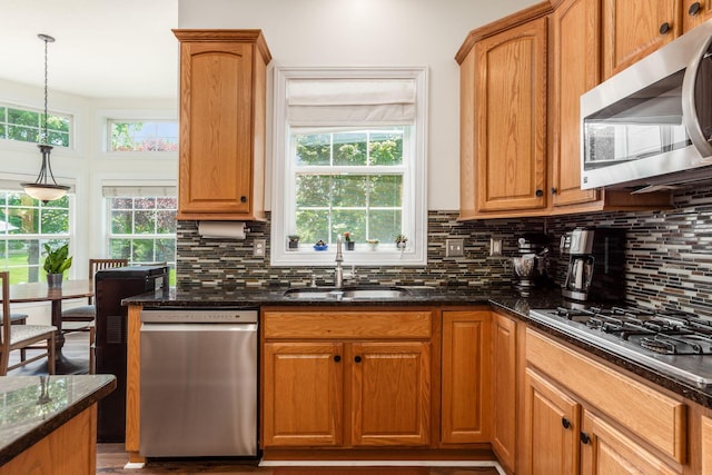 5866 Morganwood Sq, Hilliard, OH 43026 - kitchen featuring appliances with stainless steel finishes, dark stone counters, decorative backsplash, and hanging light fixtures