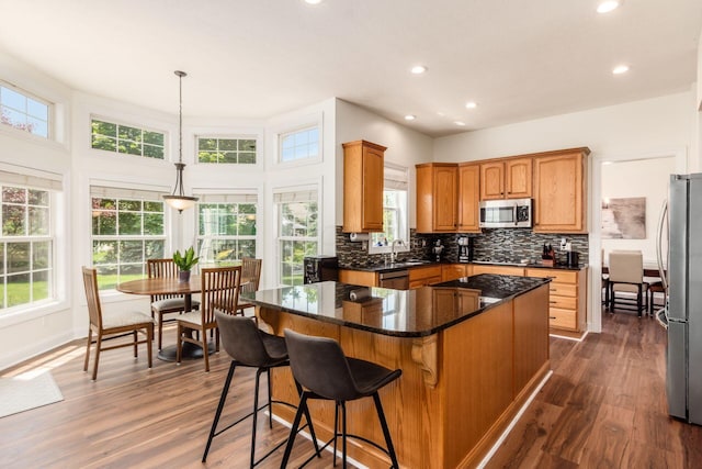 5866 Morganwood Sq, Hilliard, OH 43026 - kitchen with appliances with stainless steel finishes, a center island, recessed lighting, decorative backsplash, and dark wood-style flooring