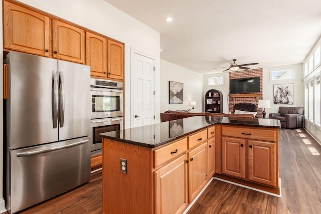 5866 Morganwood Sq, Hilliard, OH 43026 - kitchen featuring appliances with stainless steel finishes, a ceiling fan, open floor plan, a fireplace, and dark wood-style floors