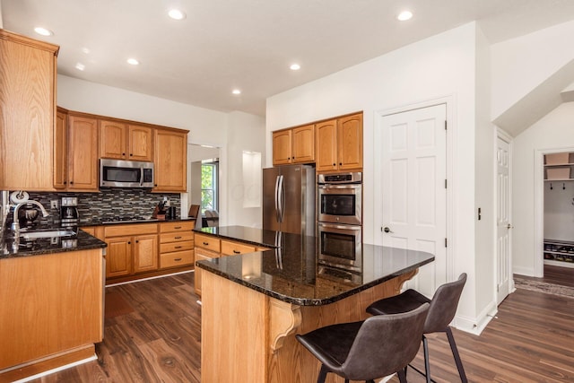 5866 Morganwood Sq, Hilliard, OH 43026 - kitchen featuring appliances with stainless steel finishes, a center island, dark wood-type flooring, decorative backsplash, and dark stone counters