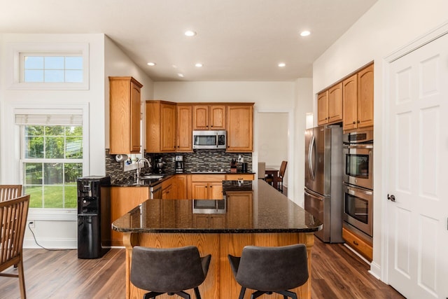 5866 Morganwood Sq, Hilliard, OH 43026 - kitchen featuring appliances with stainless steel finishes, dark wood-style floors, a center island, decorative backsplash, and recessed lighting