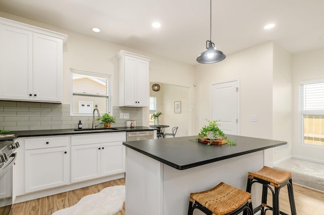 605 Frebis Ave, Columbus, OH 43206 - kitchen with dark countertops, a kitchen breakfast bar, white cabinets, light wood-style flooring, and decorative backsplash