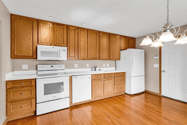 159 Hathaway Rd, West Jefferson, OH 43162 - kitchen with white appliances, a chandelier, light wood-style flooring, brown cabinetry, and light countertops