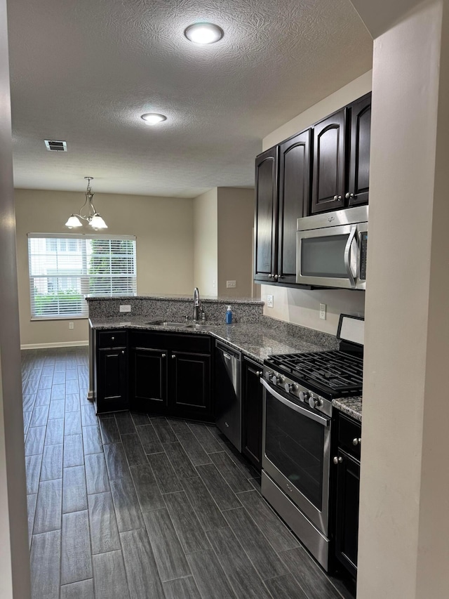 3757 Birkland Cir, Lewis Center, OH 43035 - kitchen featuring stainless steel appliances, dark wood-type flooring, a textured ceiling, a peninsula, and a chandelier