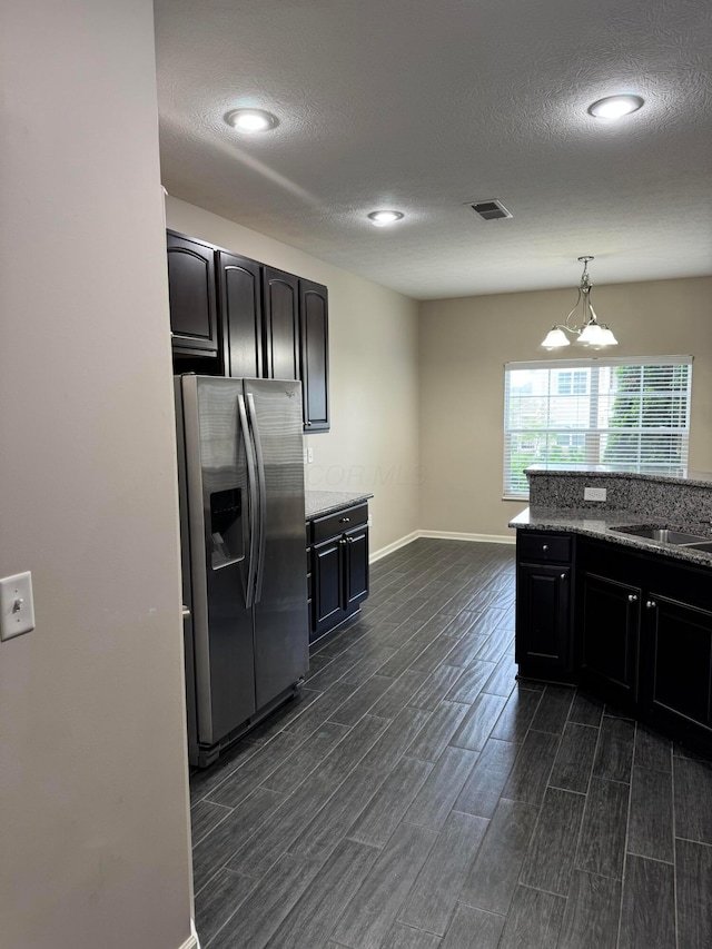 3757 Birkland Cir, Lewis Center, OH 43035 - kitchen featuring stainless steel fridge, dark wood-style floors, a chandelier, a textured ceiling, and light stone counters