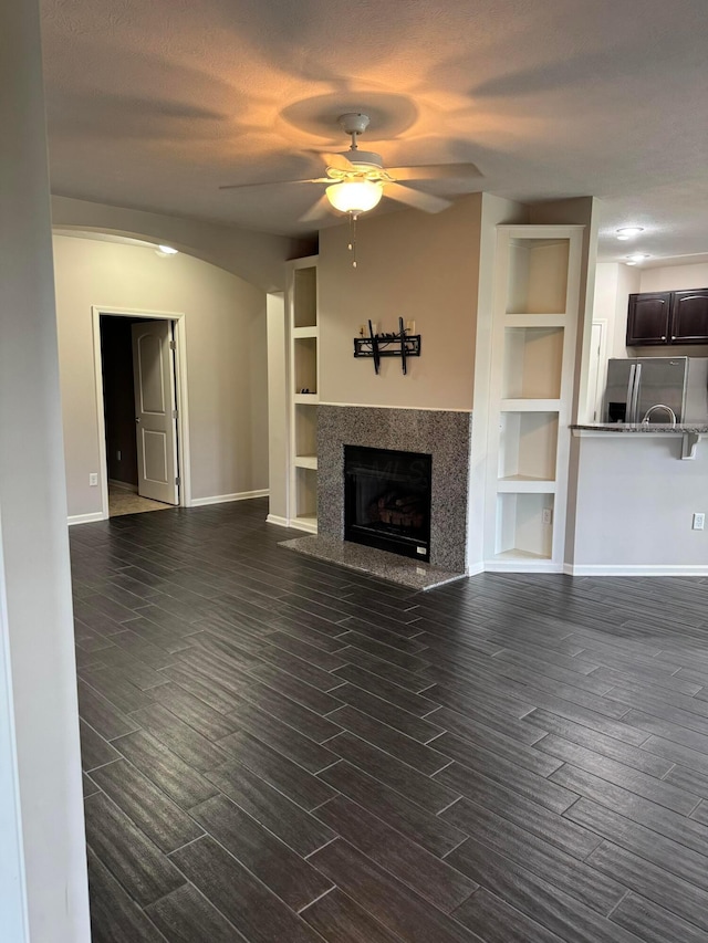 3757 Birkland Cir, Lewis Center, OH 43035 - unfurnished living room featuring ceiling fan, dark wood-type flooring, built in shelves, a high end fireplace, and arched walkways