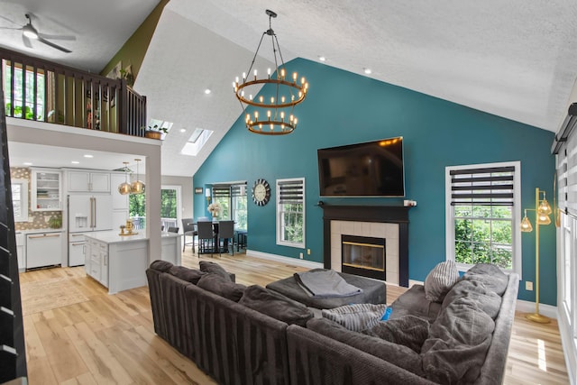 168 Thornapple Trl, Delaware, OH 43015 - living room featuring high vaulted ceiling, a chandelier, a tiled fireplace, light wood-style floors, and a textured ceiling