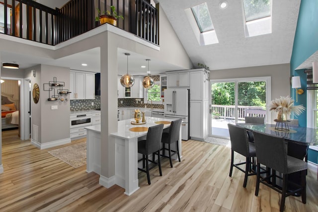 168 Thornapple Trl, Delaware, OH 43015 - kitchen with white appliances, high vaulted ceiling, light wood-style flooring, tasteful backsplash, and a breakfast bar area