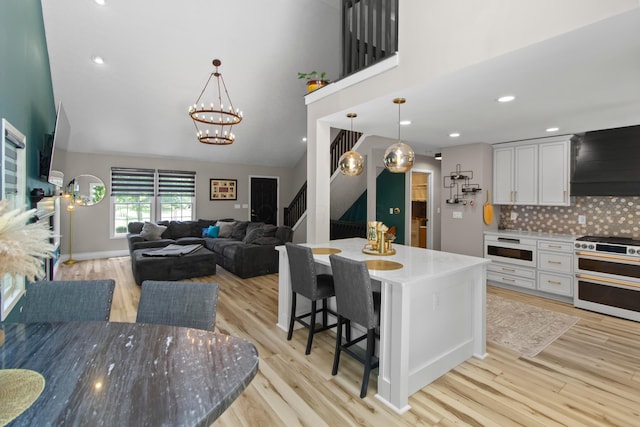168 Thornapple Trl, Delaware, OH 43015 - kitchen featuring double oven range, wall chimney range hood, light wood-style floors, a chandelier, and white cabinetry