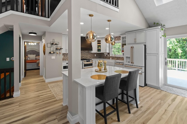 168 Thornapple Trl, Delaware, OH 43015 - kitchen with white appliances, wall chimney exhaust hood, light wood finished floors, plenty of natural light, and high vaulted ceiling