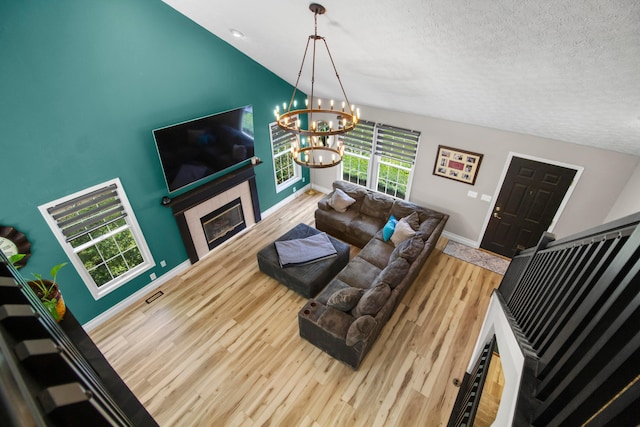 168 Thornapple Trl, Delaware, OH 43015 - living room with a textured ceiling, wood finished floors, a chandelier, a glass covered fireplace, and vaulted ceiling