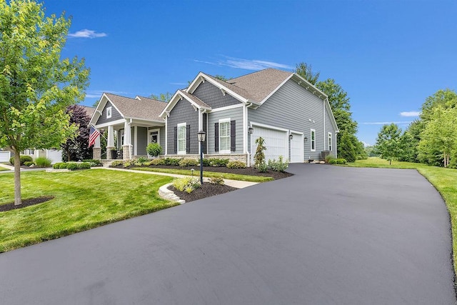 3017 Highland Woods Blvd, New Albany, OH 43054 - craftsman-style house with asphalt driveway, a front yard, stone siding, and an attached garage