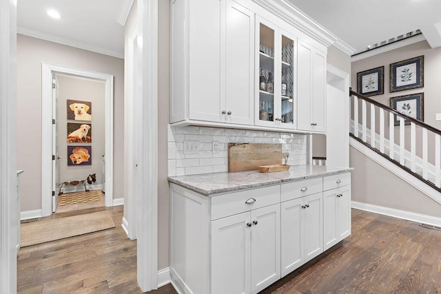 3017 Highland Woods Blvd, New Albany, OH 43054 - bar area featuring dark wood-style floors, crown molding, tasteful backsplash, stairs, and recessed lighting