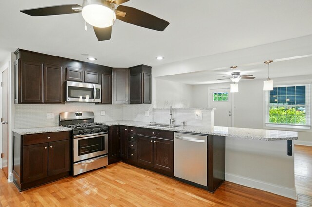 1574 River Bend Rd, Columbus, OH 43223 - kitchen with stainless steel appliances, ceiling fan, a peninsula, light wood-type flooring, and decorative backsplash