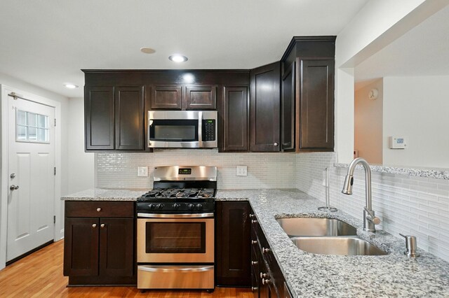 1574 River Bend Rd, Columbus, OH 43223 - kitchen featuring appliances with stainless steel finishes, light stone counters, decorative backsplash, light wood-style flooring, and dark brown cabinetry