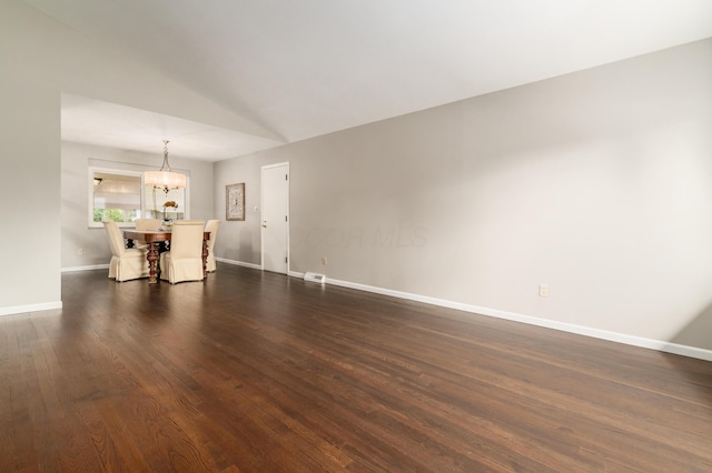 1276 Bryson Rd, Columbus, OH 43224 - unfurnished living room featuring dark wood-style flooring, a chandelier, and vaulted ceiling