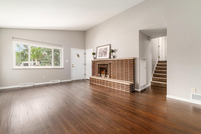 1276 Bryson Rd, Columbus, OH 43224 - unfurnished living room featuring wood finished floors, stairs, a tile fireplace, and lofted ceiling