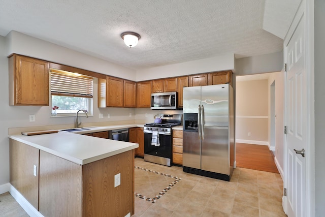 5983 Epernay Way, Galloway, OH 43119 - kitchen featuring appliances with stainless steel finishes, a peninsula, brown cabinetry, light countertops, and light tile patterned floors