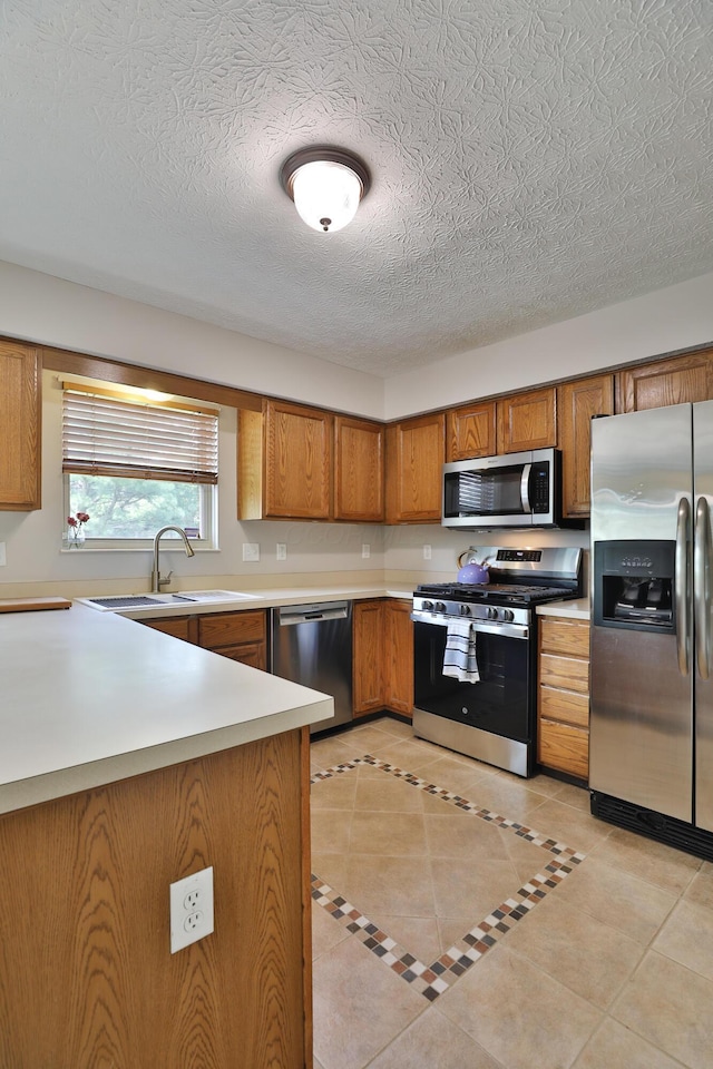 5983 Epernay Way, Galloway, OH 43119 - kitchen featuring appliances with stainless steel finishes, brown cabinets, light countertops, light tile patterned flooring, and a textured ceiling