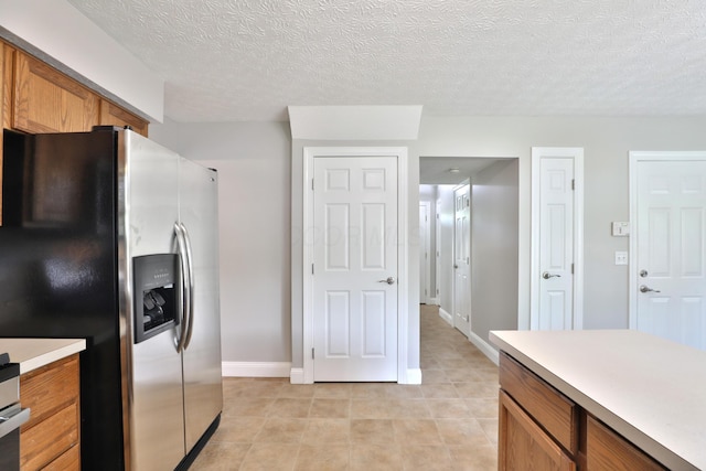 5983 Epernay Way, Galloway, OH 43119 - kitchen with stainless steel refrigerator with ice dispenser, brown cabinets, light countertops, a textured ceiling, and light tile patterned flooring