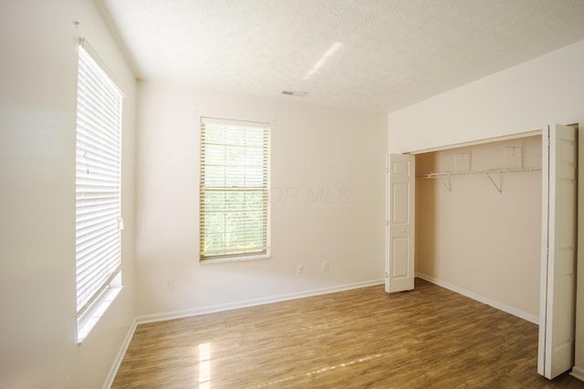 147 Shadymere Ln, Columbus, OH 43213 - unfurnished bedroom with wood finished floors, multiple windows, a closet, and a textured ceiling