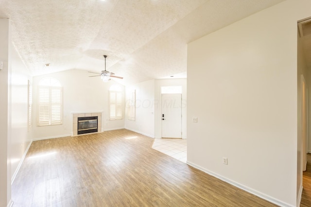147 Shadymere Ln, Columbus, OH 43213 - unfurnished living room with a ceiling fan, light wood-type flooring, lofted ceiling, a fireplace, and a textured ceiling