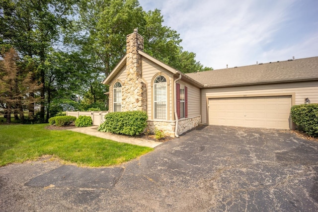 147 Shadymere Ln, Columbus, OH 43213 - view of front facade with stone siding, asphalt driveway, a chimney, a front yard, and a garage