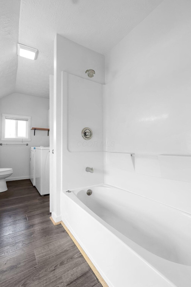 212 S Pickaway St, Circleville, OH 43113 - bathroom featuring washing machine and clothes dryer, wood finished floors, a textured ceiling, tub / shower combination, and vaulted ceiling