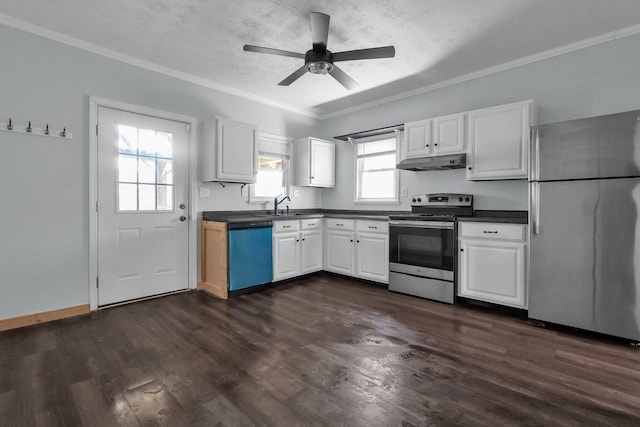 212 S Pickaway St, Circleville, OH 43113 - kitchen with appliances with stainless steel finishes, under cabinet range hood, dark countertops, white cabinetry, and ornamental molding