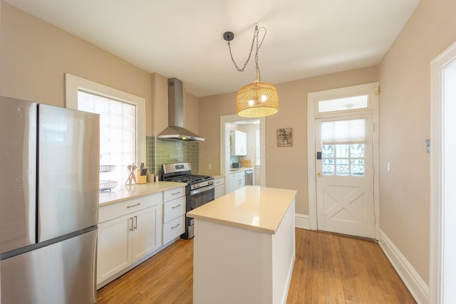 56 S Champion Ave, Columbus, OH 43205 - kitchen with stainless steel appliances, wall chimney range hood, light wood-type flooring, backsplash, and light countertops