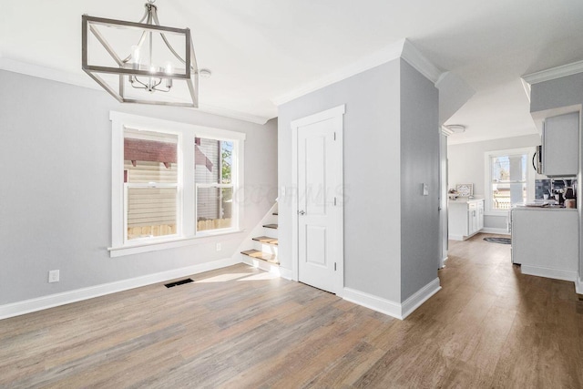 670-672 E Jenkins Ave, Columbus, OH 43207 - unfurnished dining area featuring crown molding, wood finished floors, a chandelier, plenty of natural light, and stairs