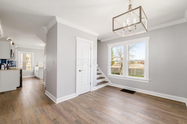 670-672 E Jenkins Ave, Columbus, OH 43207 - unfurnished dining area with crown molding, wood finished floors, a chandelier, and stairs
