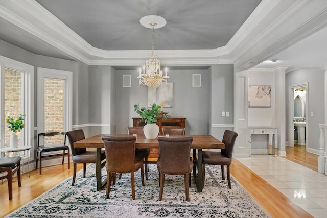 3917 Tarrington Ln, Columbus, OH 43220 - dining room featuring a chandelier, a tray ceiling, light wood finished floors, and ornamental molding