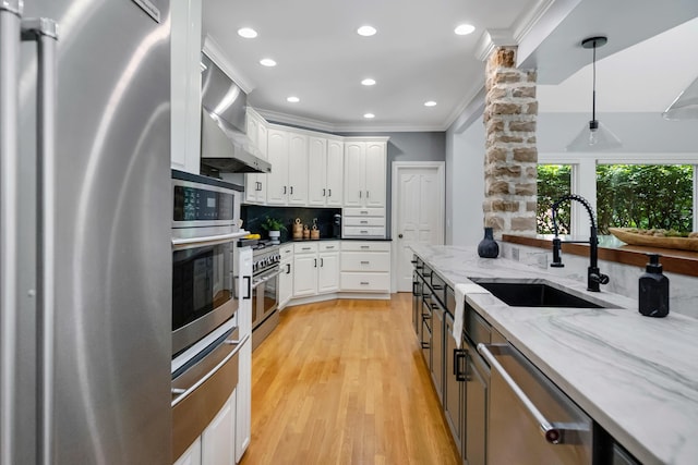 3917 Tarrington Ln, Columbus, OH 43220 - kitchen featuring appliances with stainless steel finishes, wall chimney exhaust hood, white cabinetry, backsplash, and hanging light fixtures