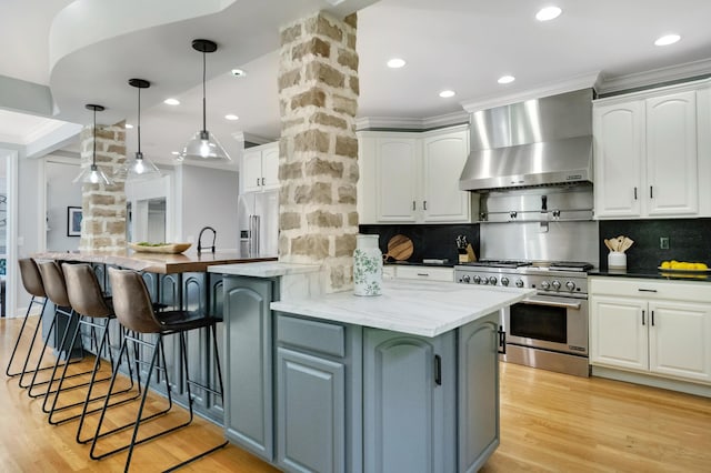 3917 Tarrington Ln, Columbus, OH 43220 - kitchen with wall chimney range hood, high quality appliances, white cabinets, crown molding, and tasteful backsplash
