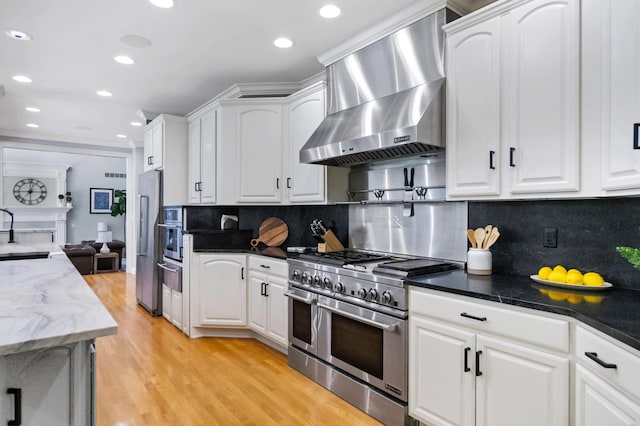 3917 Tarrington Ln, Columbus, OH 43220 - kitchen with stainless steel appliances, wall chimney range hood, a warming drawer, white cabinets, and recessed lighting