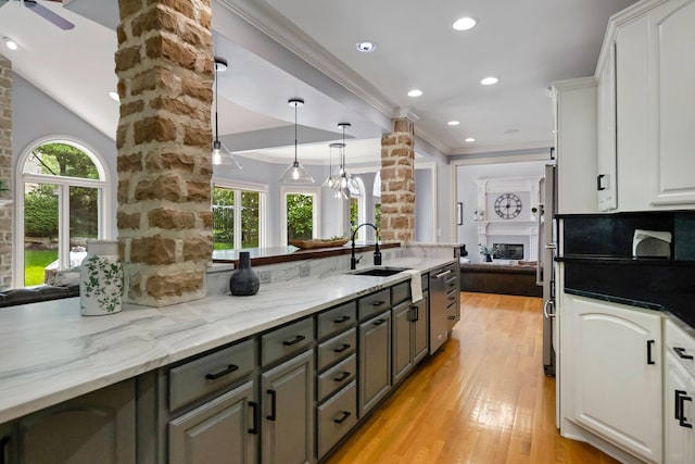 3917 Tarrington Ln, Columbus, OH 43220 - kitchen featuring ornate columns, light wood-style floors, white cabinets, light stone counters, and a glass covered fireplace