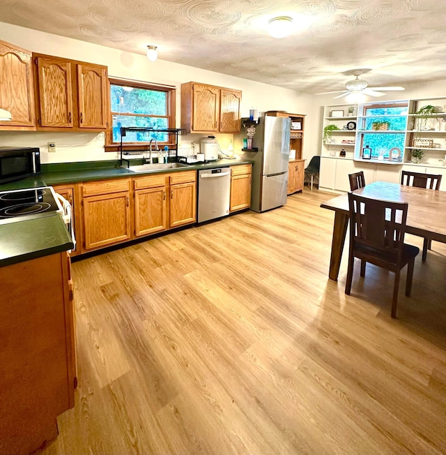 158 Kennedy Blvd, Leesburg, OH 45135 - kitchen featuring stainless steel appliances, dark countertops, brown cabinetry, ceiling fan, and light wood-style flooring