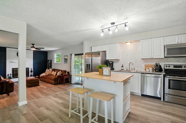 248 Grandview Ave, Delaware, OH 43015 - kitchen with stainless steel appliances, a breakfast bar area, light wood-type flooring, white cabinets, and a textured ceiling