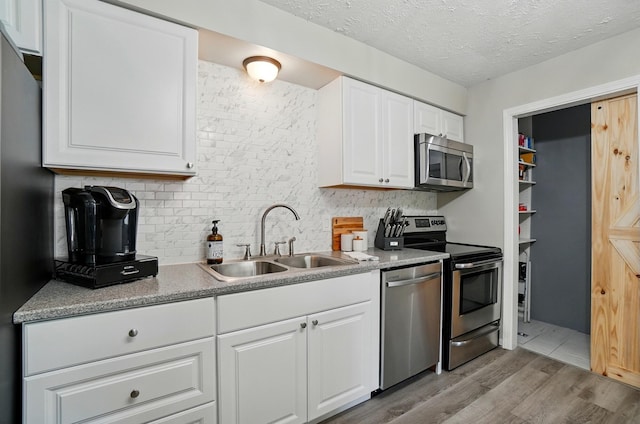 248 Grandview Ave, Delaware, OH 43015 - kitchen featuring stainless steel appliances, light wood-style flooring, decorative backsplash, white cabinetry, and a textured ceiling