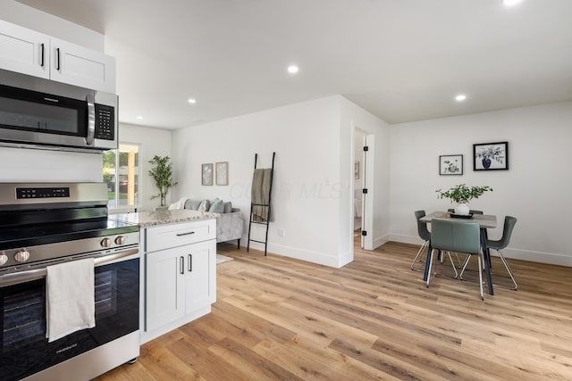 540 Mohawk Dr, Lancaster, OH 43130 - kitchen featuring appliances with stainless steel finishes, light wood finished floors, recessed lighting, white cabinets, and light stone counters