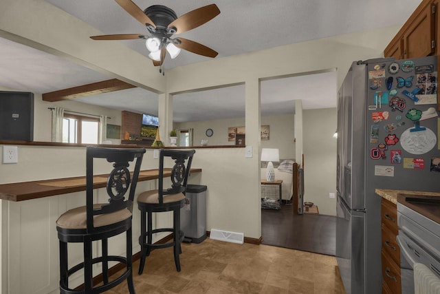 2542 Eckert Rd, Lexington, OH 44904 - kitchen featuring ceiling fan, freestanding refrigerator, a kitchen bar, and brown cabinets