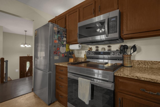 2542 Eckert Rd, Lexington, OH 44904 - kitchen with appliances with stainless steel finishes, brown cabinetry, a chandelier, light stone counters, and light tile patterned flooring