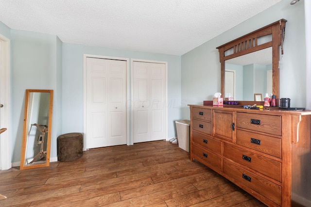 8621 Renford Ct, Powell, OH 43065 - bedroom featuring two closets, wood-type flooring, and a textured ceiling