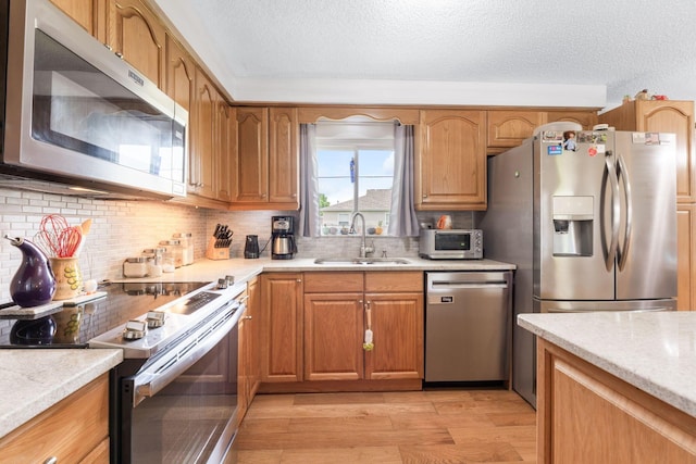 8621 Renford Ct, Powell, OH 43065 - kitchen featuring appliances with stainless steel finishes, light wood-style flooring, a textured ceiling, tasteful backsplash, and brown cabinets
