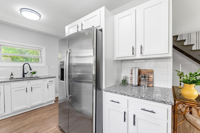 3920 Astor Ave, Columbus, OH 43227 - kitchen featuring stainless steel refrigerator with ice dispenser, backsplash, white cabinets, light stone countertops, and light wood finished floors