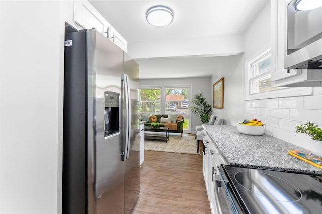 3920 Astor Ave, Columbus, OH 43227 - kitchen with appliances with stainless steel finishes, white cabinets, tasteful backsplash, wood finished floors, and light stone countertops