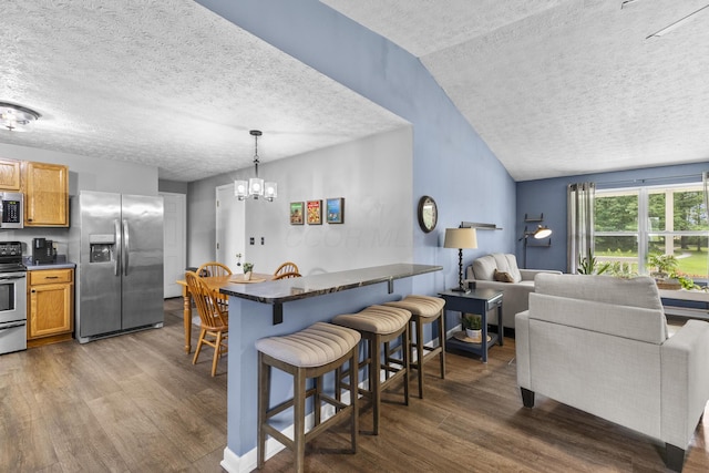 1290 Knorr Rd, Galion, OH 44833 - kitchen with stainless steel appliances, a textured ceiling, dark wood finished floors, a breakfast bar, and pendant lighting