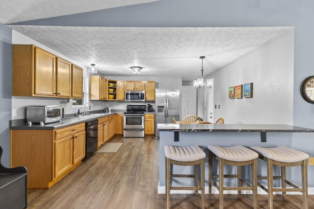 1290 Knorr Rd, Galion, OH 44833 - kitchen with appliances with stainless steel finishes, a kitchen breakfast bar, dark wood-style floors, open shelves, and hanging light fixtures