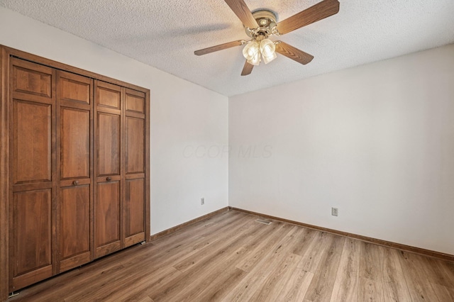 7591 Creekbend Dr, Pickerington, OH 43147 - unfurnished bedroom featuring light wood-style flooring, a textured ceiling, a closet, and a ceiling fan